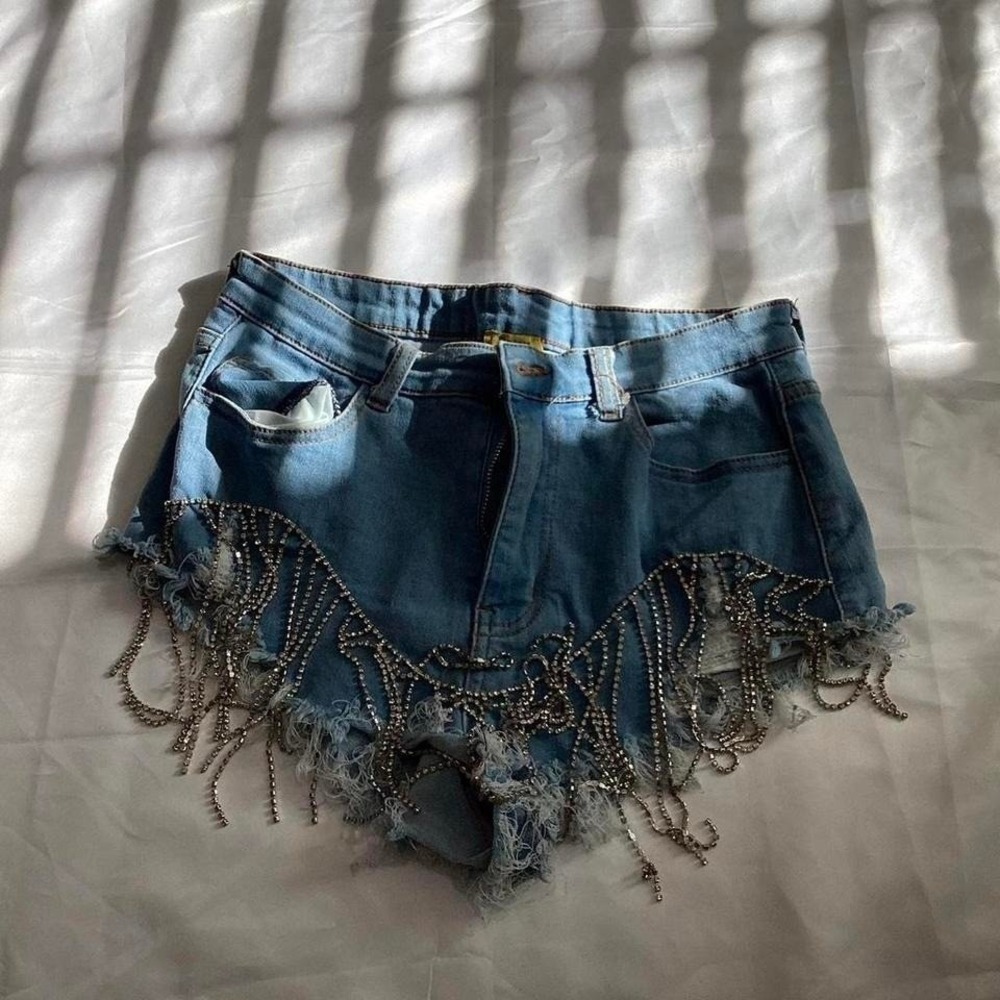 Light wash blue denim shorts with dramatic silver rhinestone fringe detailing.